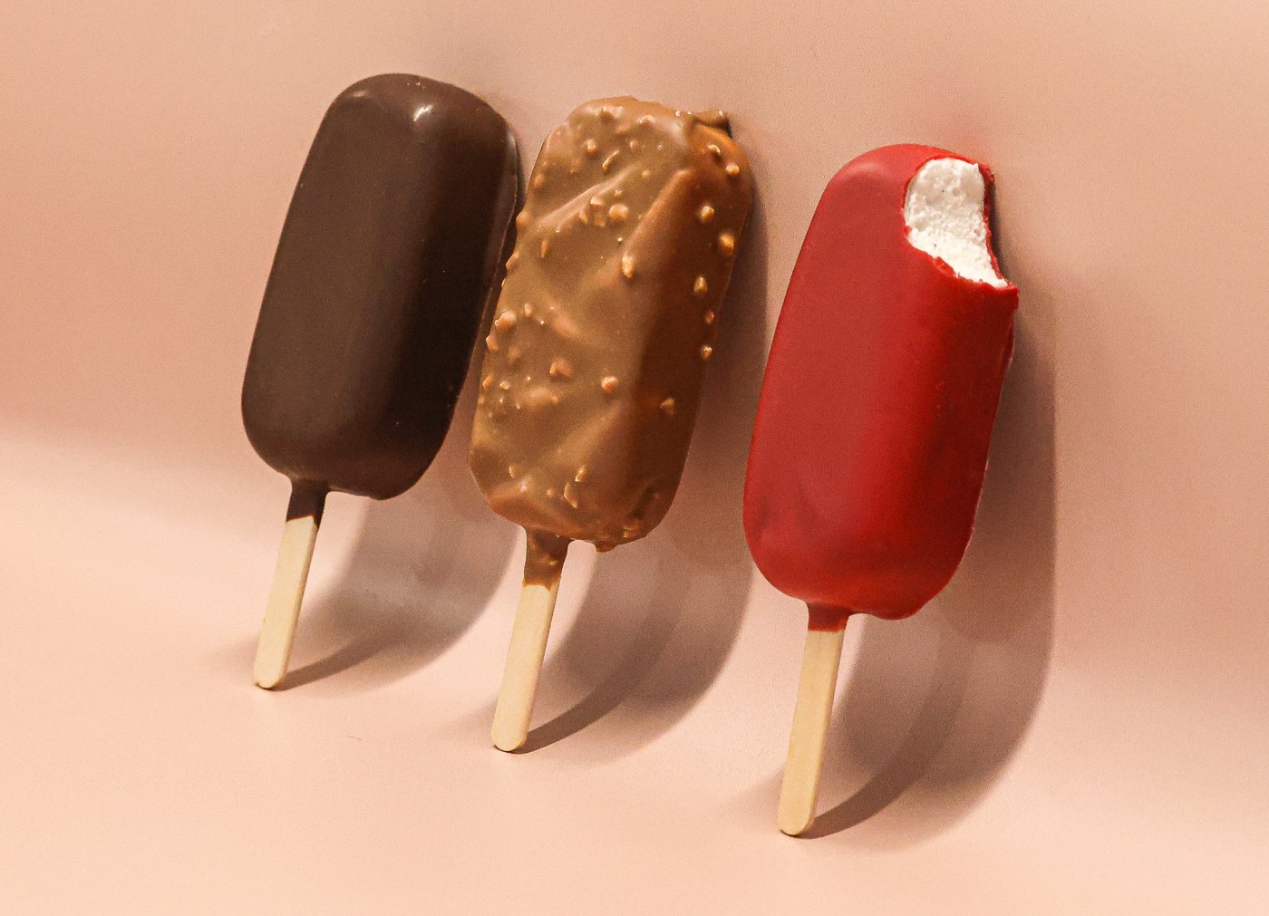 Trois bâtonnets guimauve enrobés : chocolat noir, chocolat au lait aux éclats de noisette et rouge