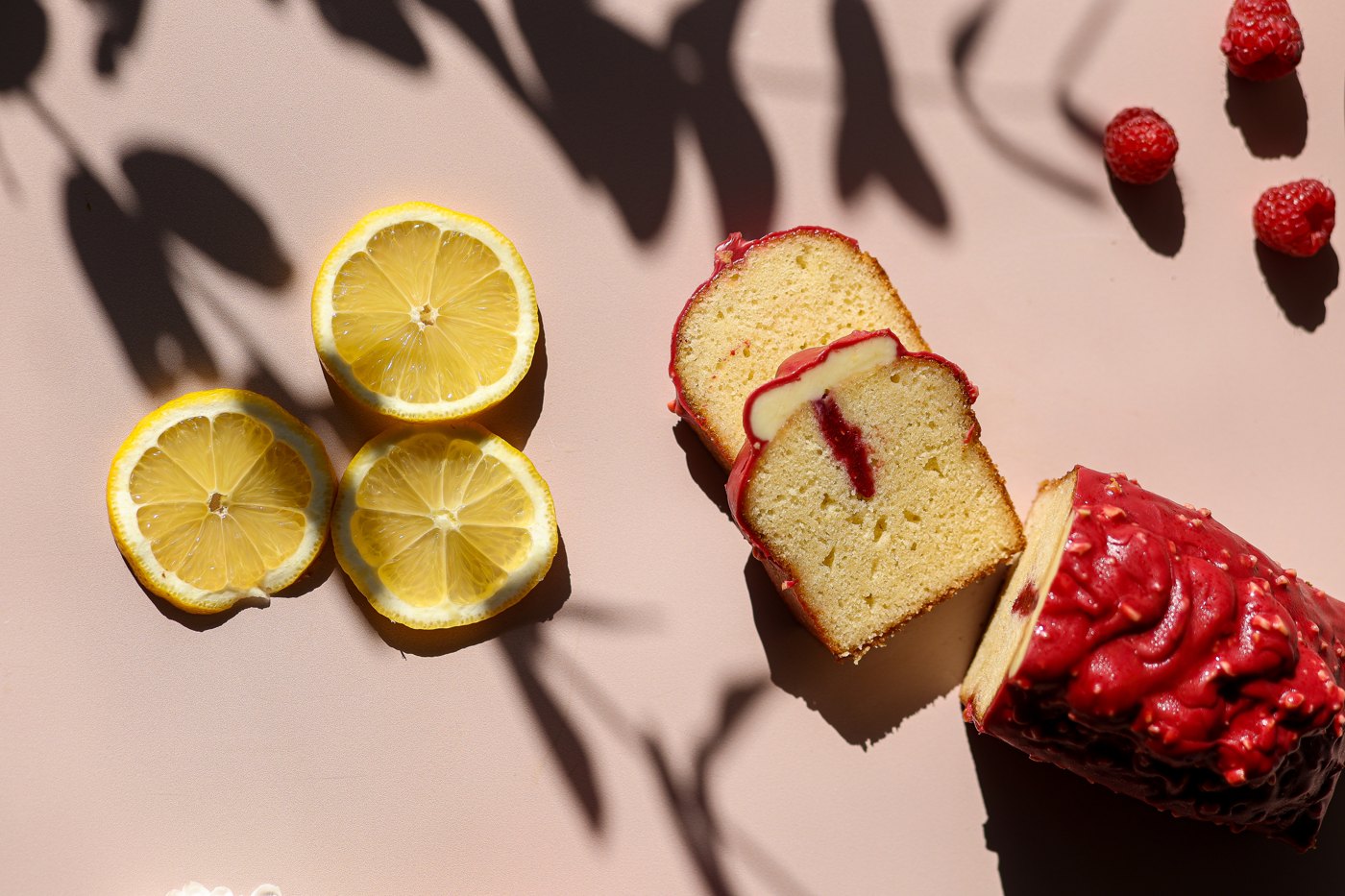 Cake au citron glacé à la framboise, tranché, avec rondelles de citron et framboises